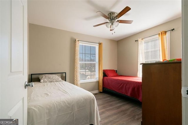 bedroom with ceiling fan, dark wood-type flooring, and multiple windows