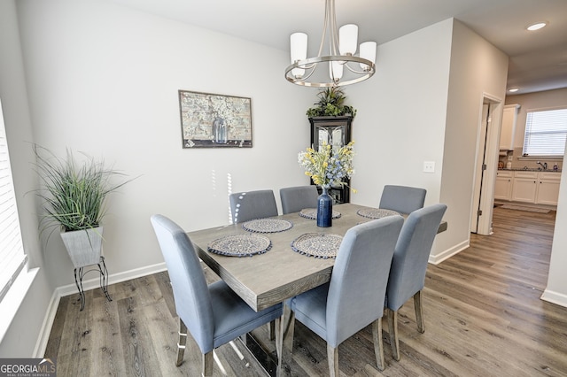 dining space with wood-type flooring, sink, and a chandelier