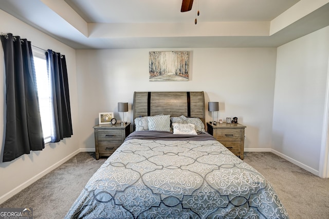 carpeted bedroom featuring a raised ceiling and ceiling fan