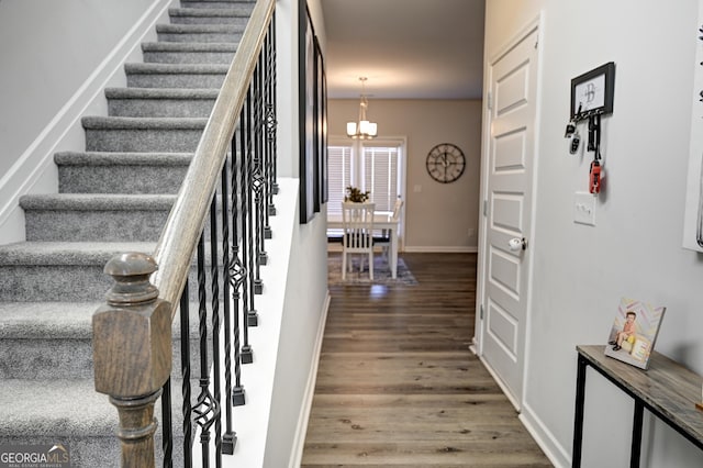 stairs with a chandelier and hardwood / wood-style flooring