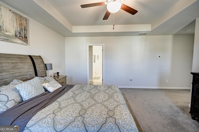 carpeted bedroom with ceiling fan, ensuite bathroom, and a raised ceiling