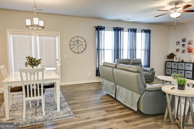 living room with ceiling fan with notable chandelier and hardwood / wood-style floors