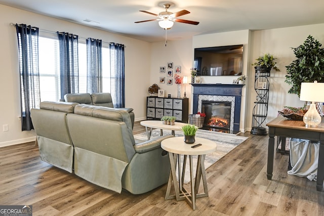 living room featuring ceiling fan, hardwood / wood-style floors, and a tile fireplace