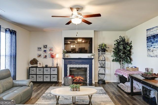 living room featuring dark hardwood / wood-style floors, a tiled fireplace, and ceiling fan