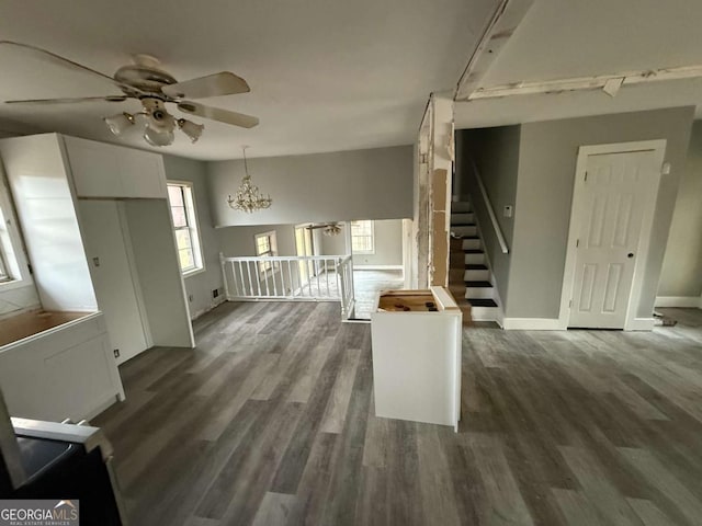 unfurnished living room with dark wood-type flooring and ceiling fan with notable chandelier