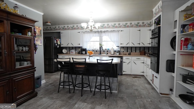 kitchen featuring white cabinets, a breakfast bar, and black appliances