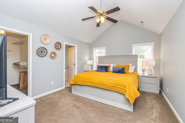 carpeted bedroom with a walk in closet, connected bathroom, a closet, vaulted ceiling, and ceiling fan