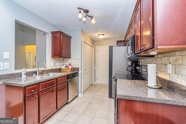 kitchen with stainless steel appliances, backsplash, light tile patterned flooring, a textured ceiling, and sink