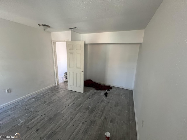 interior space with a textured ceiling and dark hardwood / wood-style floors