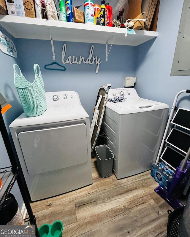 washroom with washer and clothes dryer, electric panel, and hardwood / wood-style floors