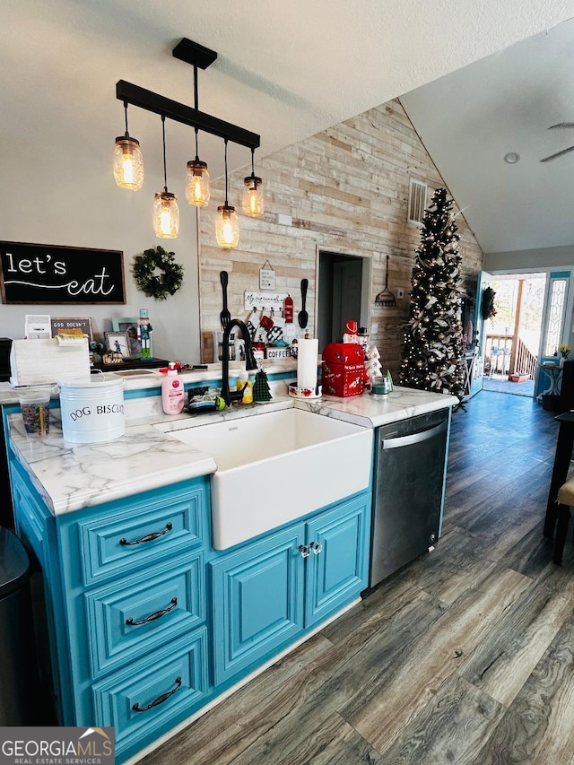 kitchen with blue cabinets, vaulted ceiling, pendant lighting, stainless steel dishwasher, and sink