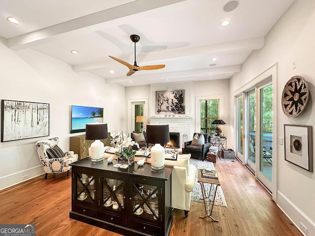 living room with hardwood / wood-style flooring, ceiling fan, and beamed ceiling