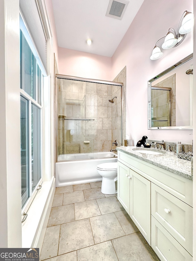 full bathroom featuring plenty of natural light, combined bath / shower with glass door, vanity, and toilet