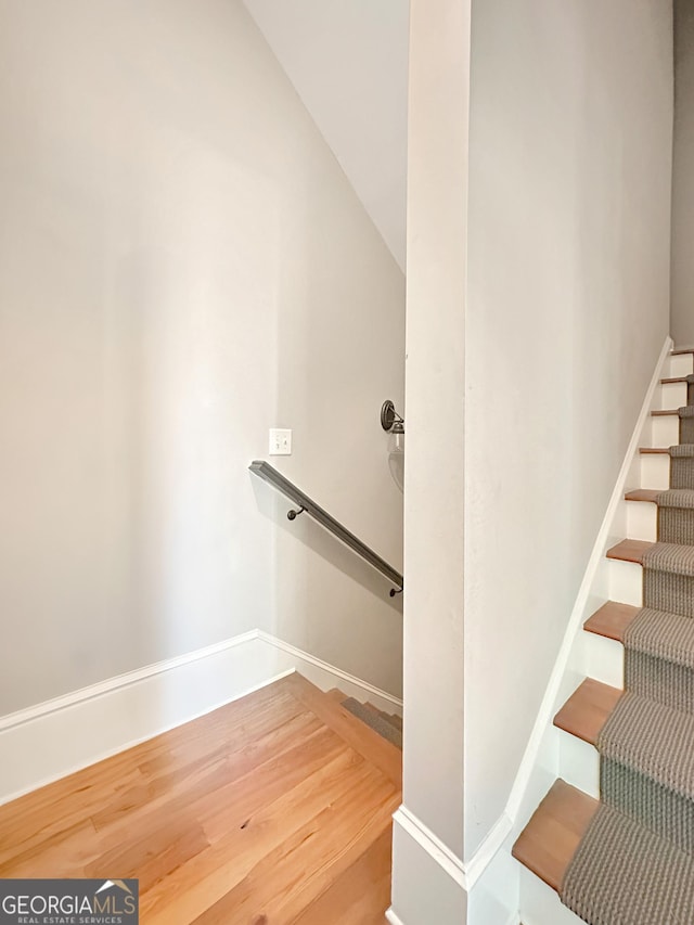 stairway with wood-type flooring and vaulted ceiling