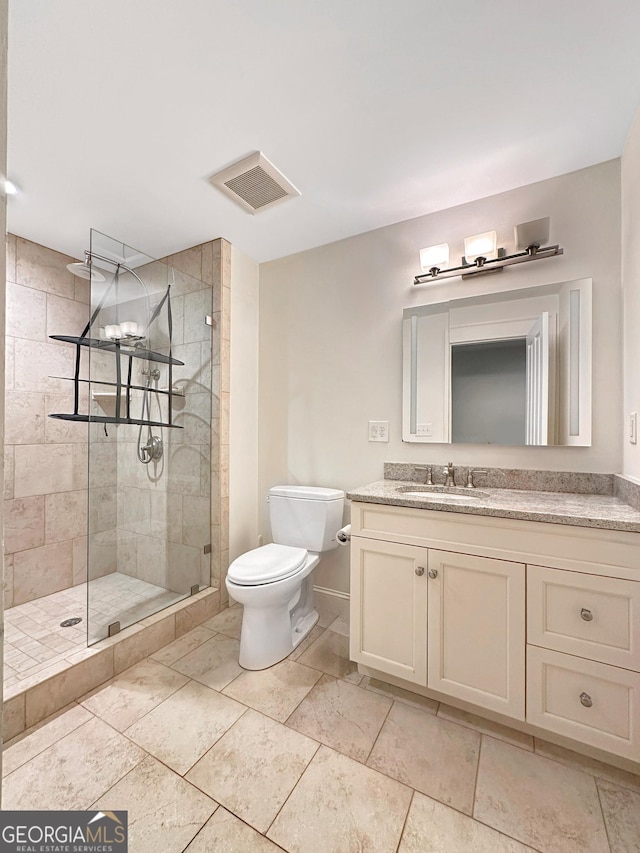 bathroom featuring toilet, vanity, and a tile shower