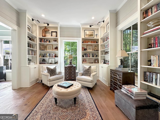 sitting room featuring hardwood / wood-style floors, built in features, and wooden walls