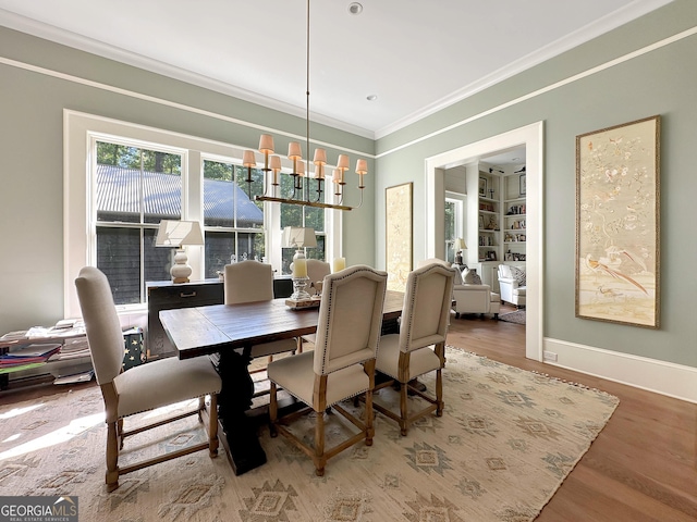 dining space with hardwood / wood-style floors, crown molding, and an inviting chandelier