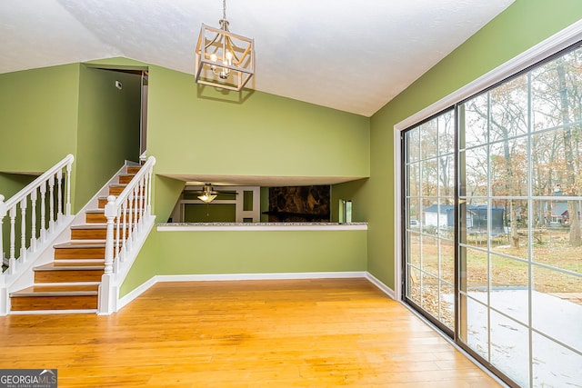 interior space featuring lofted ceiling, wood-type flooring, and an inviting chandelier