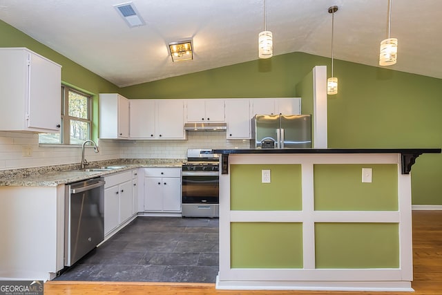 kitchen featuring decorative light fixtures, white cabinets, appliances with stainless steel finishes, and vaulted ceiling