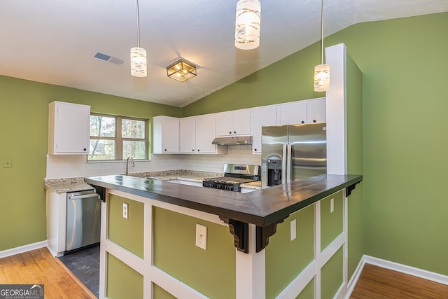 kitchen with pendant lighting, white cabinets, stainless steel appliances, and lofted ceiling