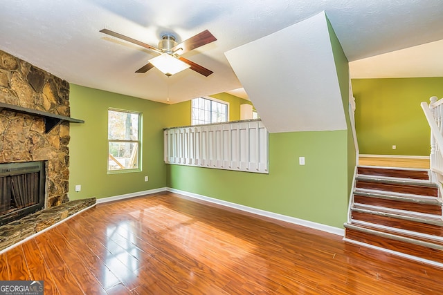 unfurnished living room with ceiling fan, hardwood / wood-style floors, vaulted ceiling, and a fireplace