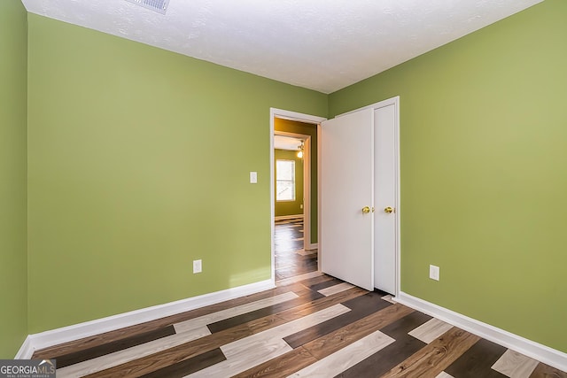 spare room featuring a textured ceiling and dark wood-type flooring