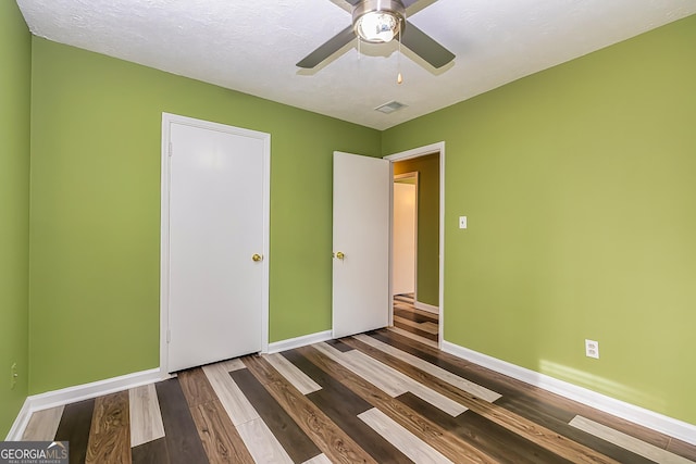 unfurnished bedroom with ceiling fan, hardwood / wood-style floors, a closet, and a textured ceiling