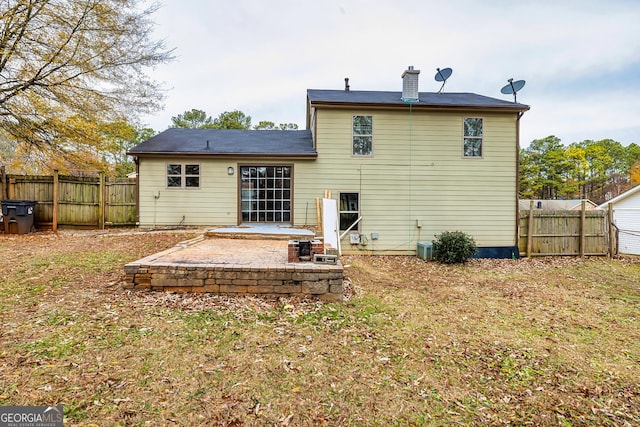 back of house with a lawn and a patio