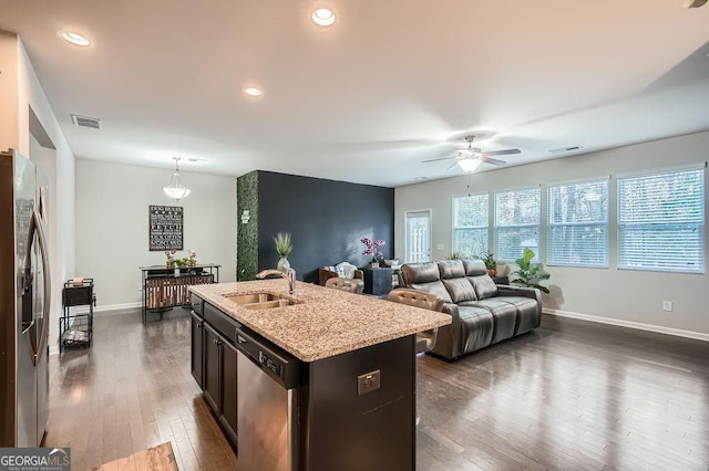 kitchen featuring appliances with stainless steel finishes, pendant lighting, an island with sink, sink, and dark wood-type flooring