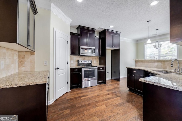 kitchen featuring pendant lighting, stainless steel appliances, sink, backsplash, and dark hardwood / wood-style floors