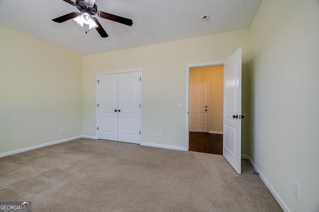 unfurnished bedroom with ceiling fan, light colored carpet, a closet, and a textured ceiling