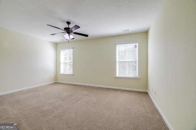 carpeted spare room with a textured ceiling and ceiling fan