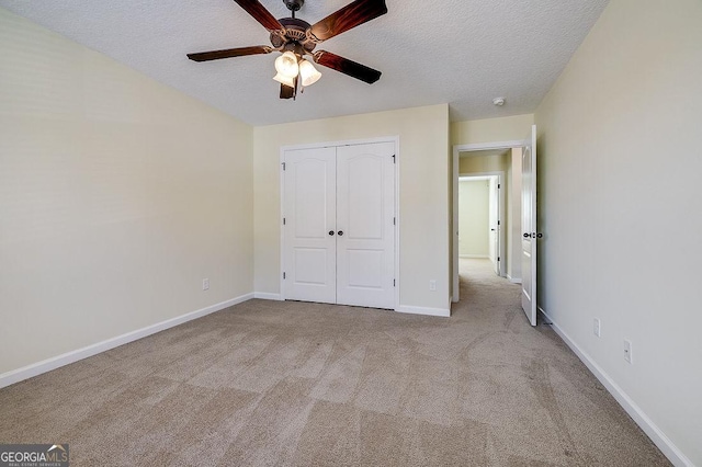 unfurnished bedroom with ceiling fan, a closet, light carpet, and a textured ceiling