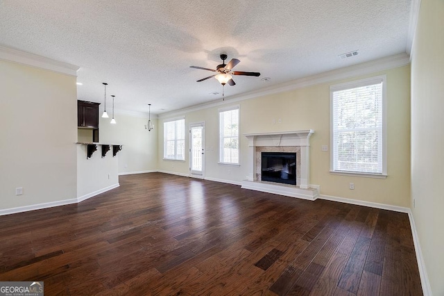 unfurnished living room featuring ceiling fan, plenty of natural light, and ornamental molding