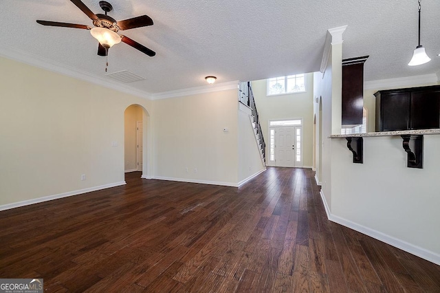 unfurnished living room with ceiling fan, dark hardwood / wood-style flooring, a textured ceiling, and ornamental molding