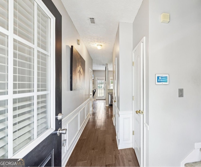 corridor with dark hardwood / wood-style floors and a textured ceiling