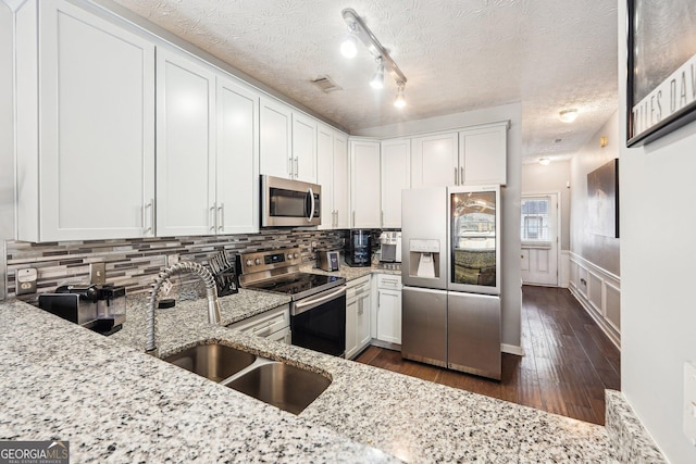 kitchen featuring light stone counters, sink, white cabinetry, and stainless steel appliances