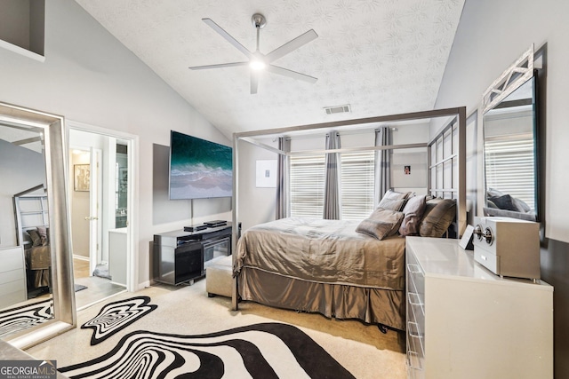 bedroom featuring light carpet, ceiling fan, vaulted ceiling, and a textured ceiling