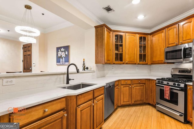 kitchen with tasteful backsplash, visible vents, brown cabinets, stainless steel appliances, and a sink