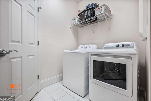 washroom with baseboards, light tile patterned flooring, laundry area, and washer and clothes dryer