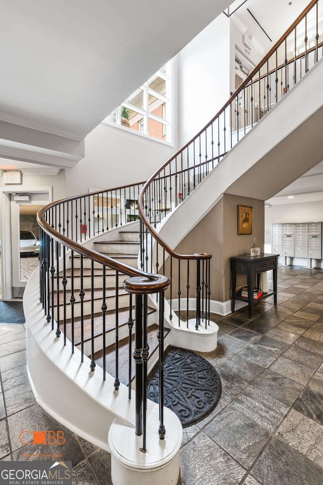 staircase with stone finish floor, a high ceiling, and baseboards