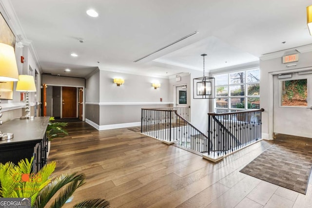 interior space with wood finished floors, baseboards, recessed lighting, ornamental molding, and an upstairs landing