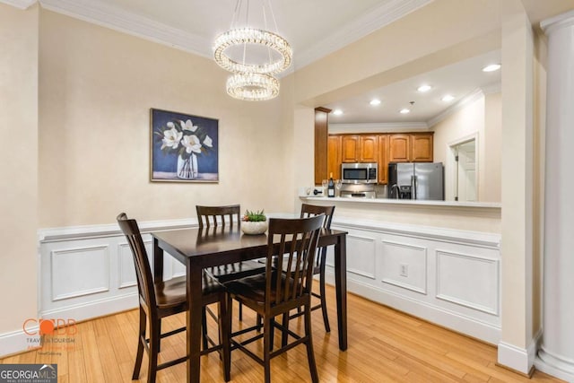 dining area featuring a notable chandelier, ornamental molding, and light wood finished floors