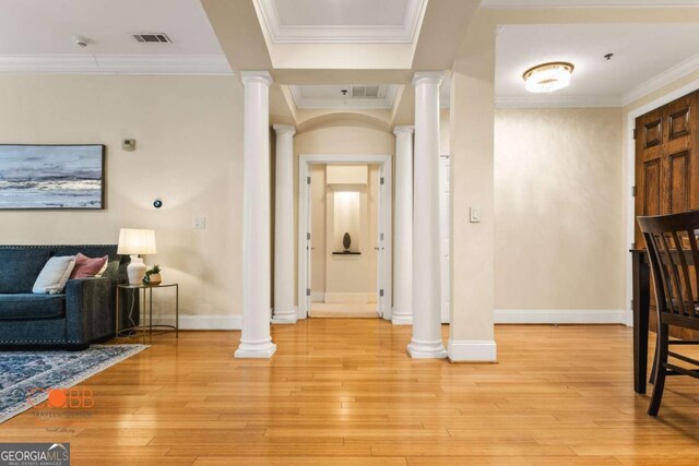 interior space featuring crown molding, light wood-style floors, and decorative columns