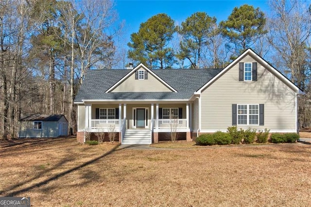 view of front of house featuring a front lawn, a storage unit, and covered porch