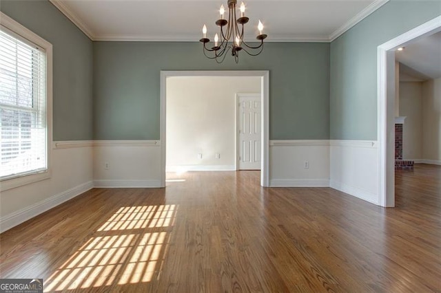 spare room featuring a notable chandelier, crown molding, and hardwood / wood-style flooring