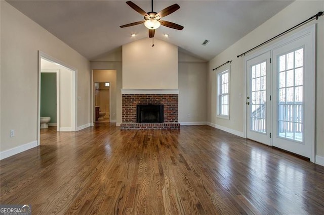 unfurnished living room with ceiling fan, vaulted ceiling, a fireplace, and dark hardwood / wood-style floors