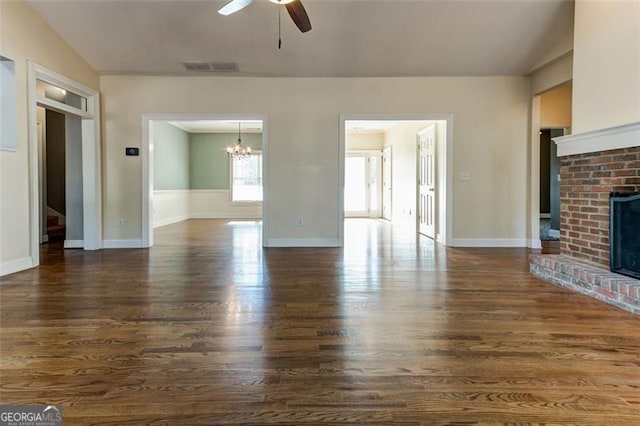 unfurnished living room featuring a fireplace, dark hardwood / wood-style flooring, and ceiling fan with notable chandelier