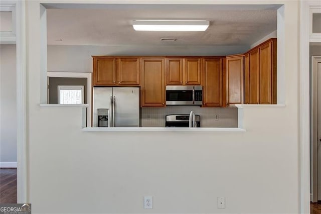 kitchen featuring kitchen peninsula, appliances with stainless steel finishes, and backsplash