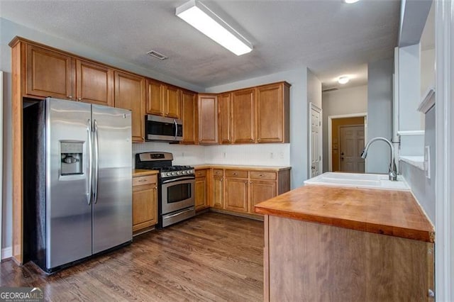 kitchen with sink, dark hardwood / wood-style floors, stainless steel appliances, and wood counters